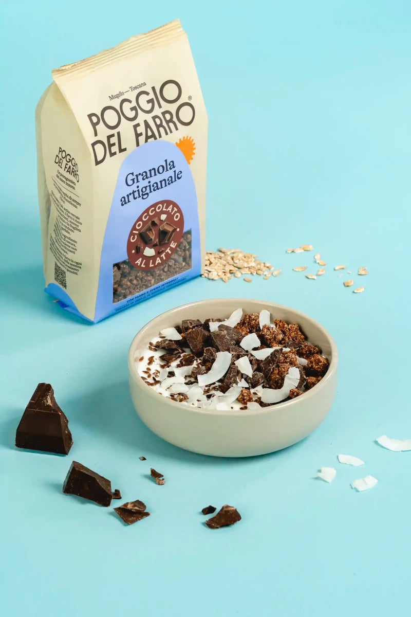 Granola artigianale con cioccolato al latte. Agglomerati croccanti messi all'interno di una bowl con dentro yogurt, cioccolato, semi di lino e chips di cocco. 
